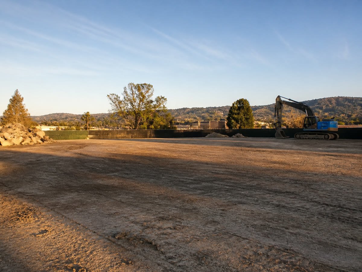 Cleared commercial lot graded for redevelopment, East Bay hills behind