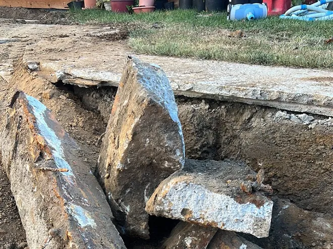 Broken concrete slab sections stacked beside the trench after removal