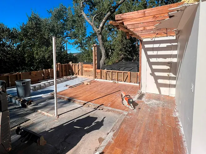 Deck and patio cover mid-teardown in a residential backyard