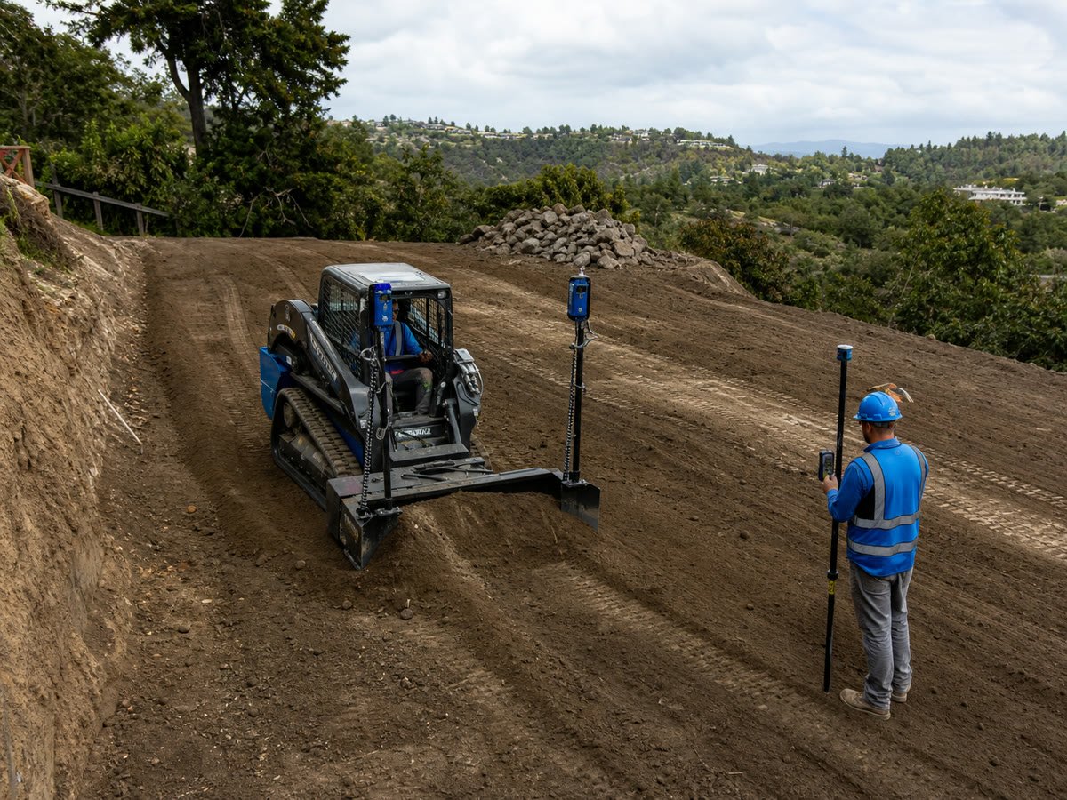 Skid steer performing precision laser grading with a receiver pole