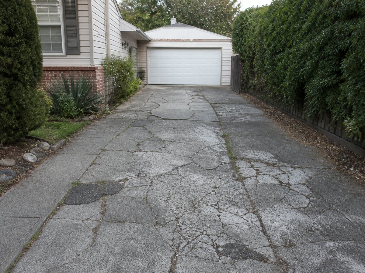 Severely worn and cracked driveway before removal