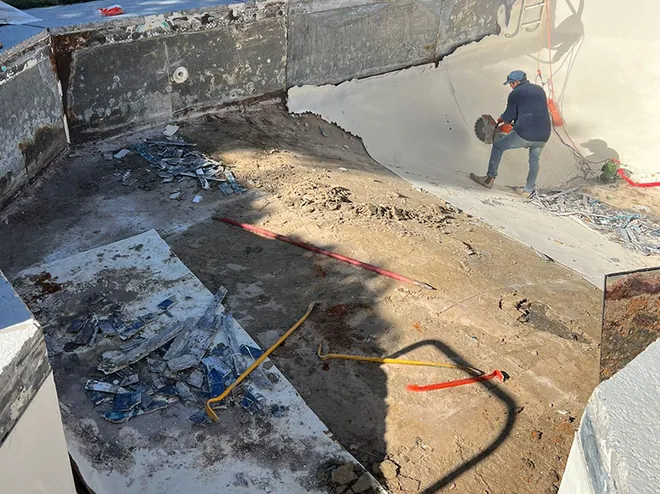 Worker breaking out a pool shell during pool removal